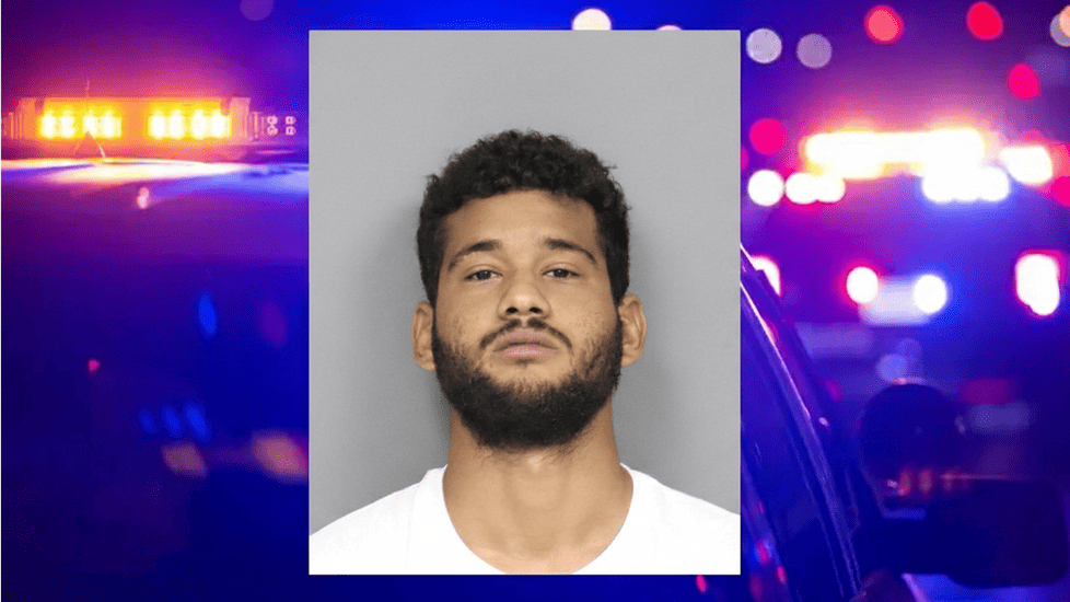 Mugshot of Anthony Garcia with short curly hair, trimmed beard, and neutral facial expression, wearing a white shirt, in front of a plain gray background.