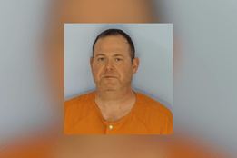 Mugshot-style photo of Dr. Thomas Shaknovsky wearing an orange jail uniform against a plain background.