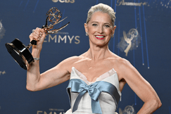 Katherine LaNasa smiles while holding her Emmy trophy at the 77th Primetime Emmy Awards, wearing a white gown with a blue bow.