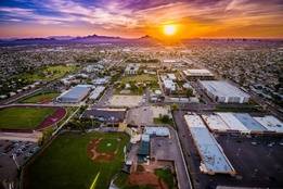 Aerial view of Grand Canyon University’s campus in Phoenix, Arizona at sunset, with athletic fields, academic buildings, and the city skyline in the distance.