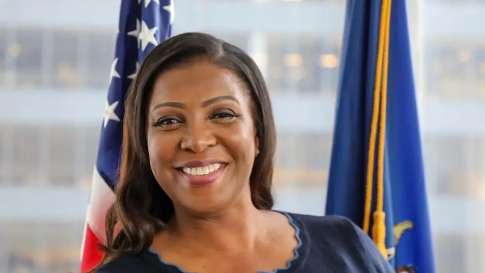 New York Attorney General Letitia James smiles in front of U.S. and state flags.