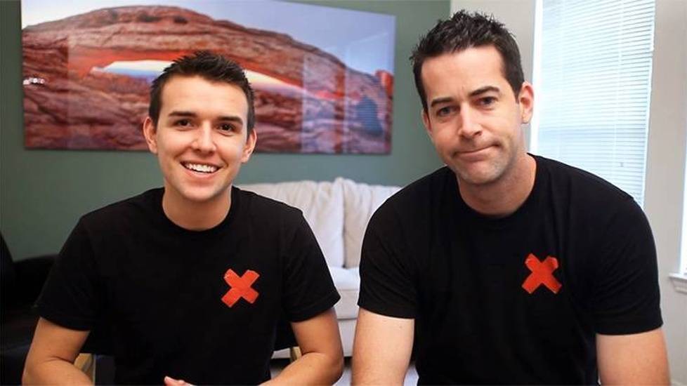 Two men in black shirts with red X over heart