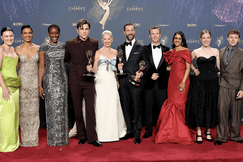 The cast and creators of 'The Pitt' pose together on the red carpet at the Emmy Awards, holding multiple trophies. The group is dressed in formal gowns and suits, standing in front of an Emmy backdrop