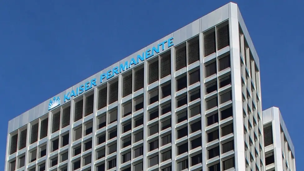 Kaiser Permanente headquarters building with the organization’s logo displayed at the top against a blue sky.