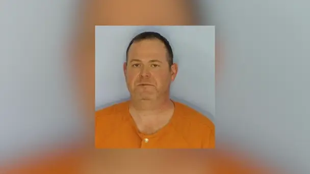 Mugshot-style photo of Dr. Thomas Shaknovsky wearing an orange jail uniform against a plain background.