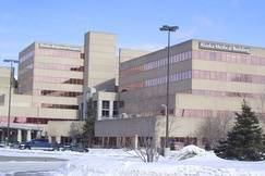 Exterior winter view of Alaska Regional Hospital and Alaska Medical Building in Anchorage, Alaska, with snow-covered ground, parked cars, and a sign reading ‘Alaska Regional’ in front of the campus.