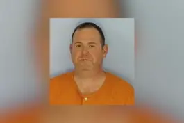 Mugshot-style photo of Dr. Thomas Shaknovsky wearing an orange jail uniform against a plain background.