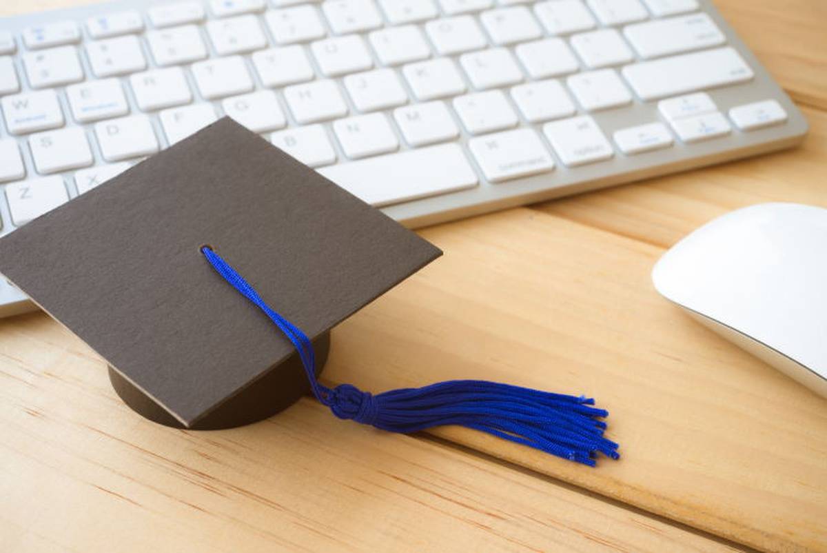 Graduation cap next to laptop on desk