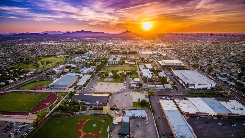 Aerial view of Grand Canyon University’s campus in Phoenix, Arizona at sunset, with athletic fields, academic buildings, and the city skyline in the distance.