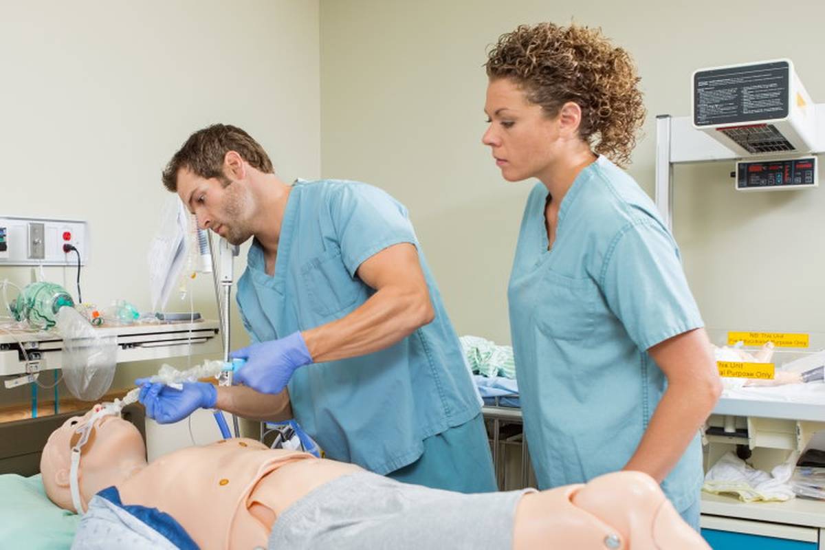 One nurse teaching another CPR on a practice dummy