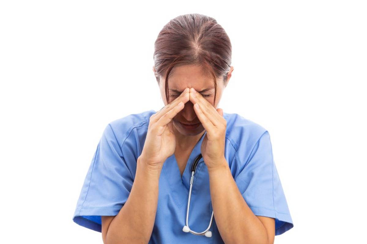 Female nurse holding fingers to head from stress