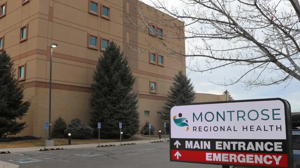 Exterior of Montrose Regional Health hospital in Colorado with a sign pointing to the main entrance and emergency department.