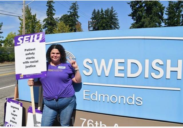 Nurse holding protest sign in front of Swedish Hospital sign